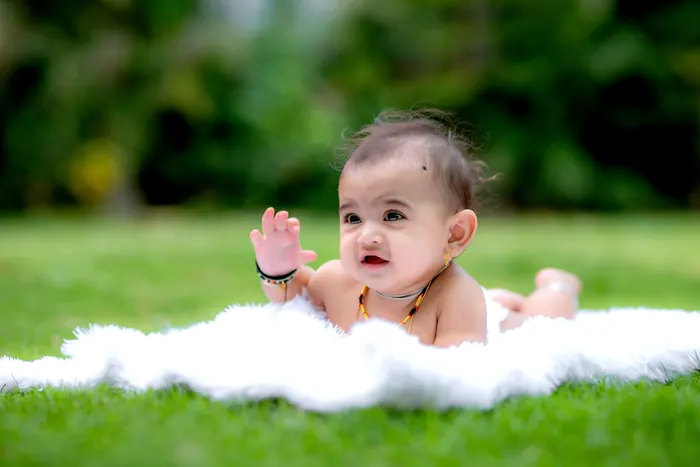 Baby lying on a white blanket during a studio milestone session