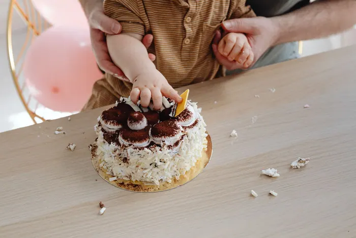 Small hands pressing into a cake at the end of a cake smash