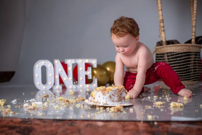 Toddler seated beside illuminated ONE letters at a first birthday shoot