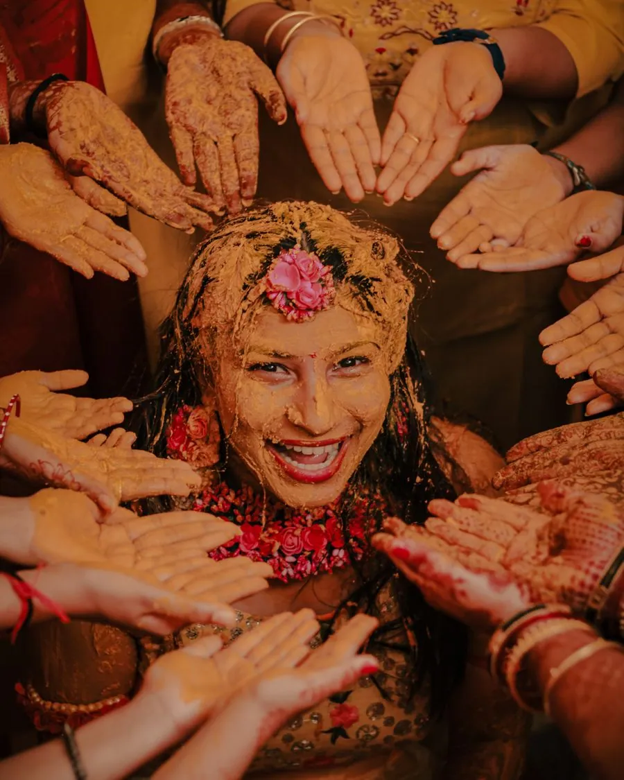 Bride surrounded by hands covered in turmeric during the haldi