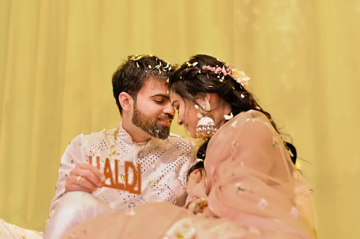 Couple close together during a turmeric ceremony, marigold garlands around them