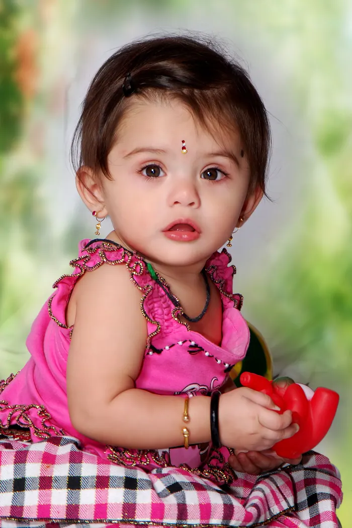 Child in a bright outfit looking straight at the camera during a studio session