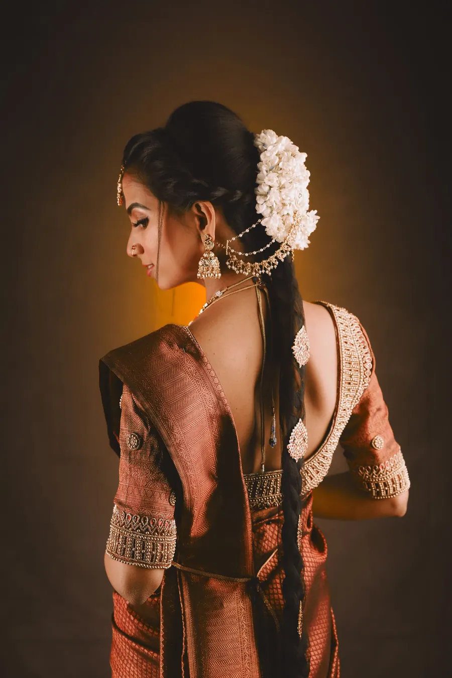Expectant mother photographed from behind in a traditional saree, mehndi across her back and arms
