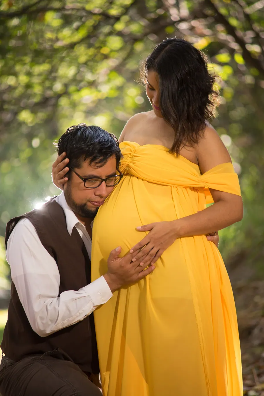 Couple together during a maternity session, both hands resting on the bump
