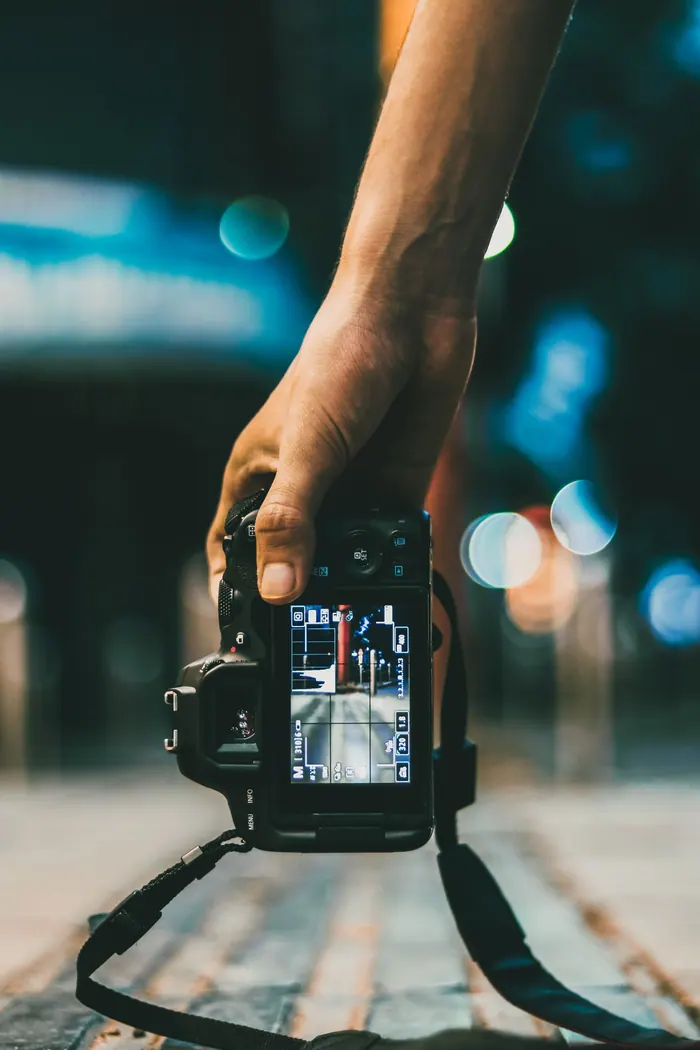 Hands holding a camera, the screen lit against a dark room