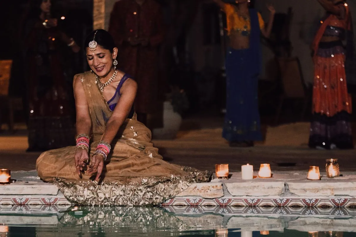Bride seated beside a row of lamps during the night ceremony