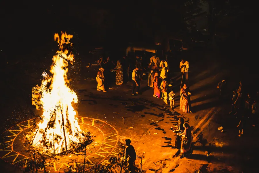 Guests gathered around a large fire at night during an outdoor wedding function