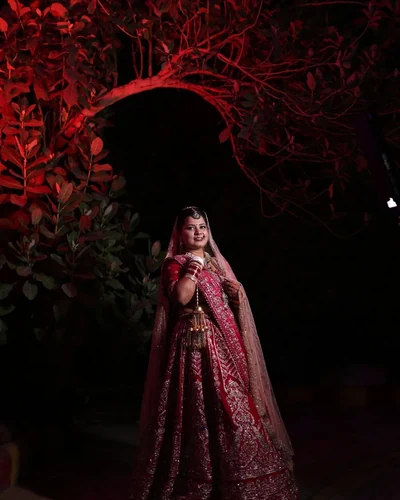 Bride seated in her red lehenga, lit from one side during the ceremony