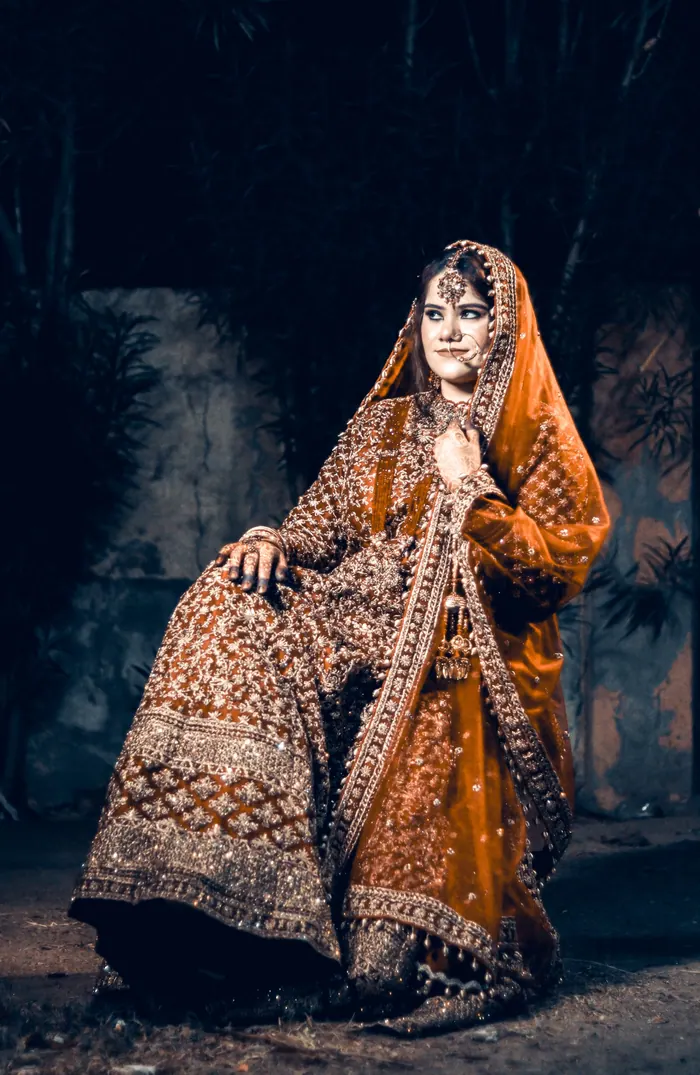Bride in an embroidered dupatta photographed against a dark wall