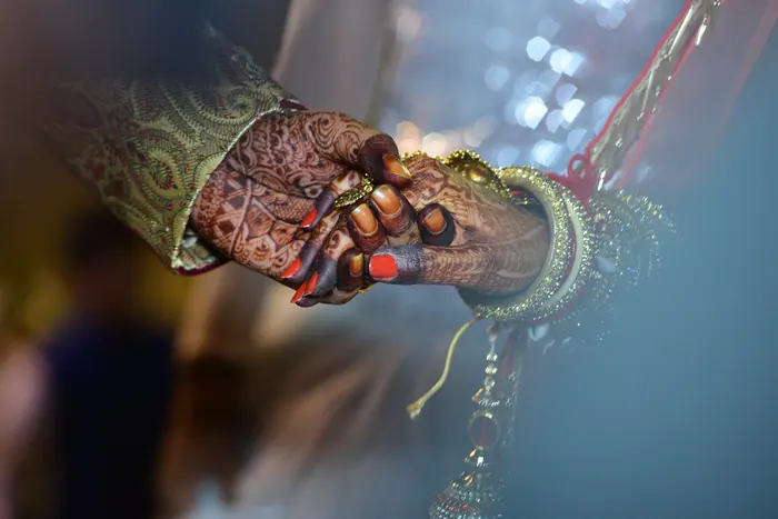 The bride's hands in red chooda resting in the groom's hands