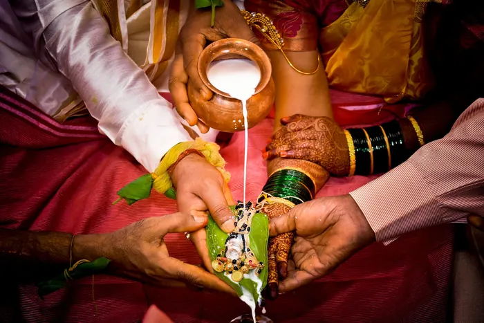 Hands pouring water over a kalash during a wedding ritual