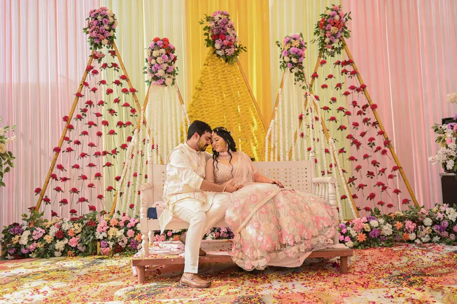 Couple seated on the decorated reception stage under a floral backdrop