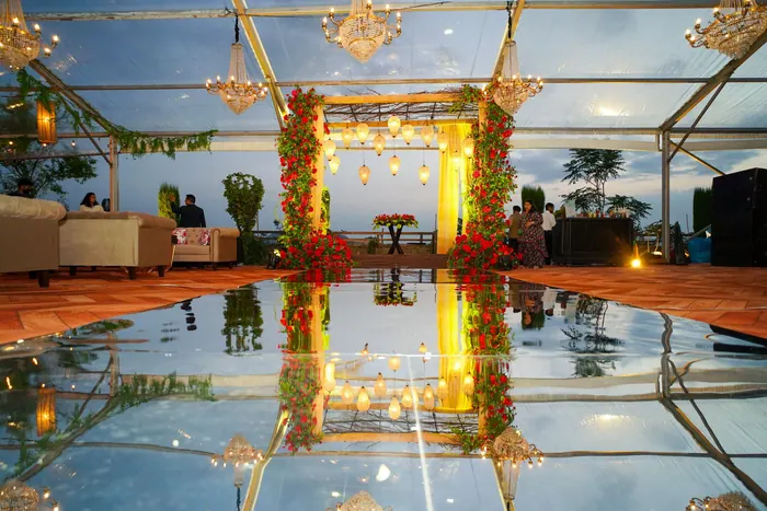 Reception venue lit after dark, the mandap reflected in water