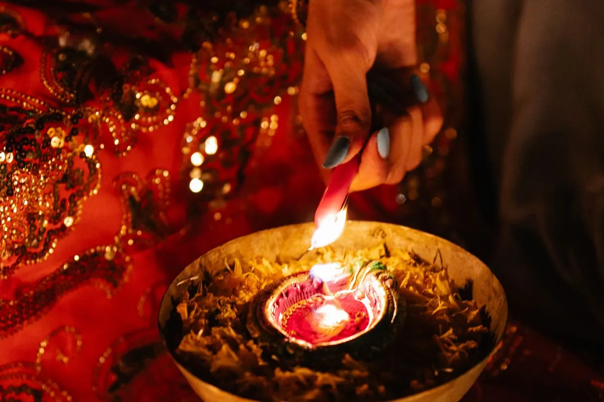 Hands holding a lit diya during an evening ritual