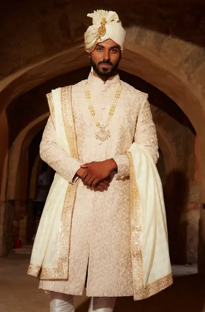 Groom in a cream sherwani photographed as a standing portrait