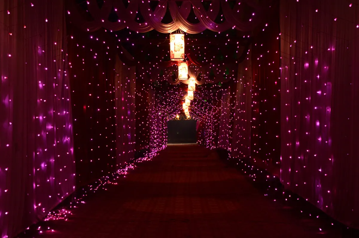Lit entrance corridor at a wedding venue after dark, curtains of small lights on both sides
